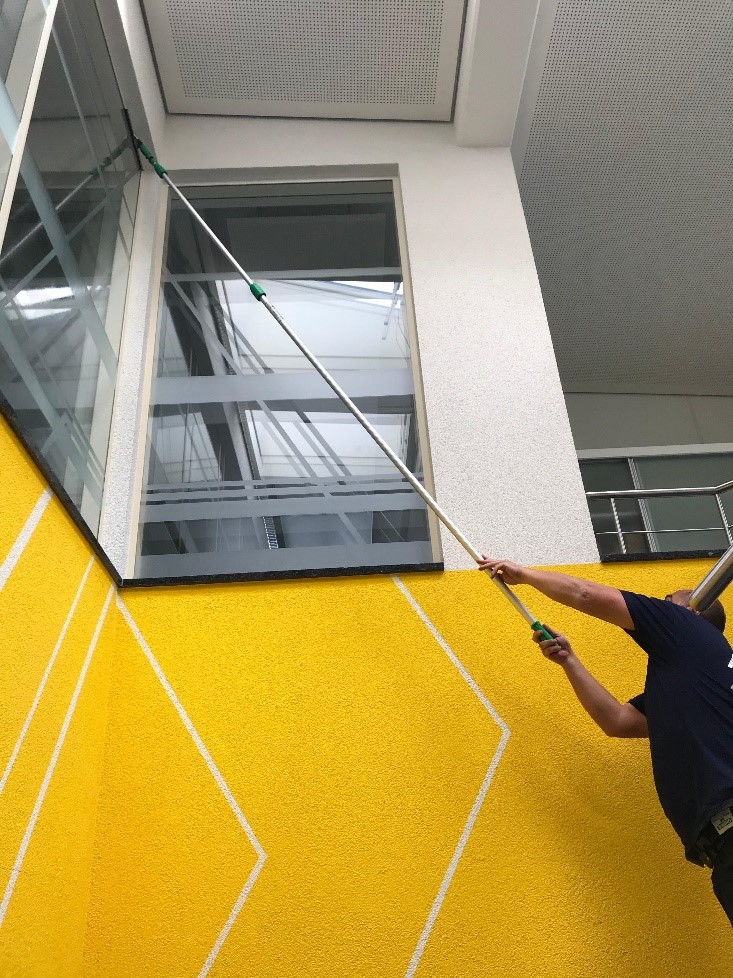 Reinigung hoher Fensterbereiche im Treppenhaus.